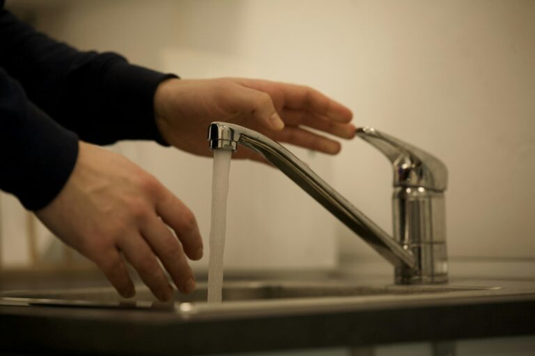 Wasserhahn aufdrehen – Hand bedient einen Einhebelmischer an der Küchenspüle